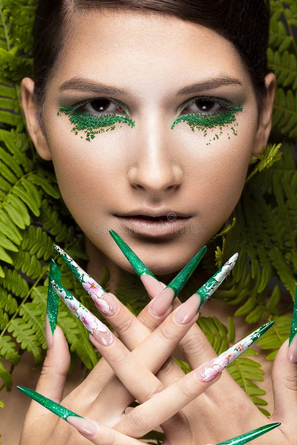 Beautiful girl with art make-up, fern leaves and long nails. Manicure design. The beauty of the face.