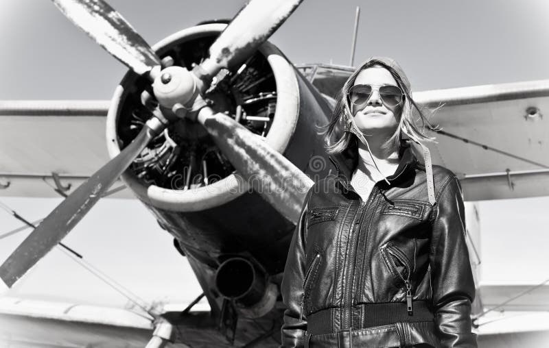 Beautiful girl in black jacket standing on a war aircraft.