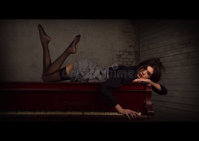 Girl wearing black & white striped stockings sitting on a piano