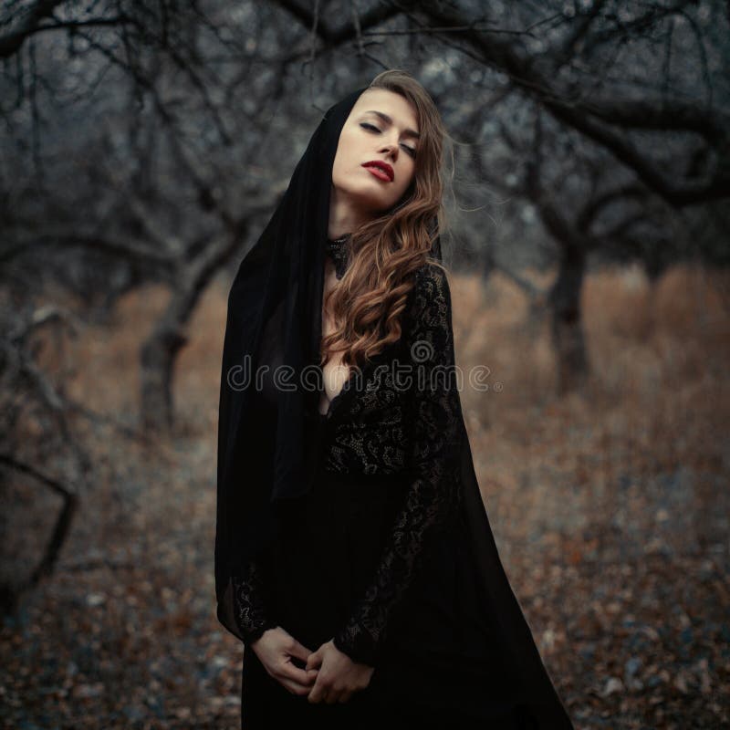 Beautiful girl in in black vintage dress with curly hair posing in the woods. Woman in retro dress lost in the forest. Worried sen royalty free stock images Beautiful girl in in black vintage dress with curly hair posing in the woods. Woman in retro dress lost in the forest. Worried sen royalty free stock images