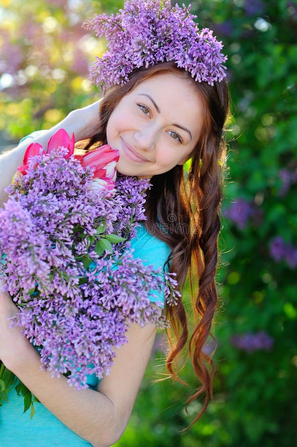 Beautiful girl with a bouquet of lilac walking in spring park