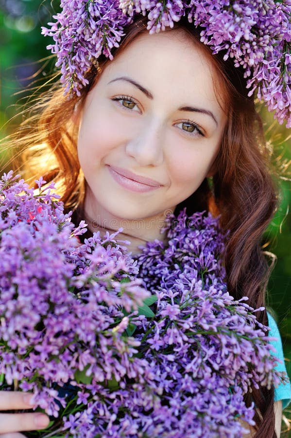 Beautiful girl with a bouquet of lilacs and a wreath of lilac