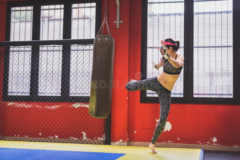 Beautiful girl boxing against punching bag