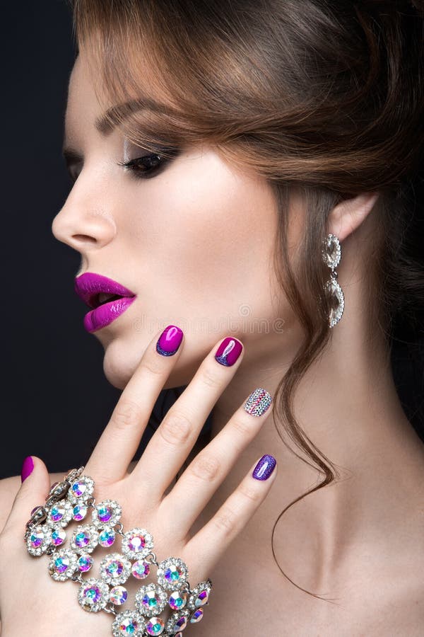 Beautiful girl with a bright evening make-up and purple manicure with rhinestones. Nail design. Beauty face. stock photo Beautiful girl with a bright evening make-up and purple manicure with rhinestones. Nail design. Beauty face. stock photo
