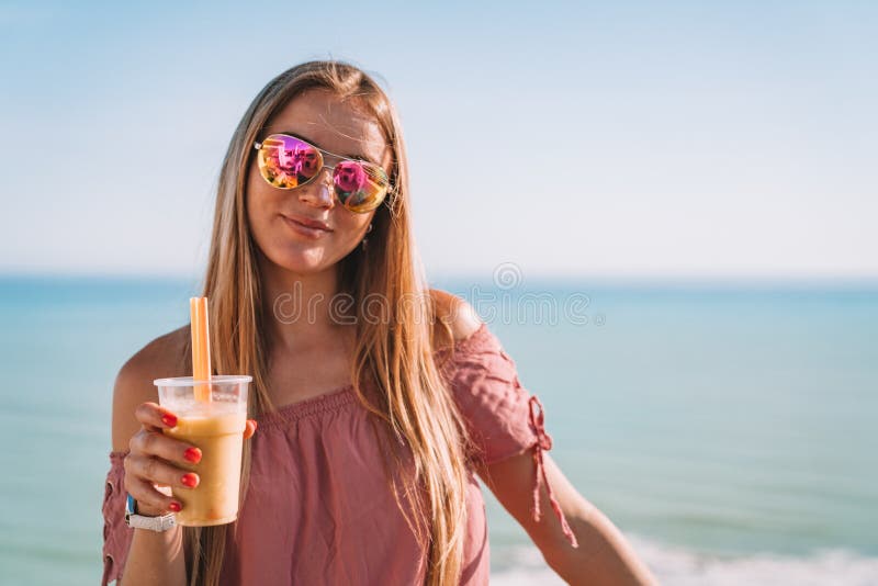 Beautiful girl in a colorful sunglasses drinking cocktail