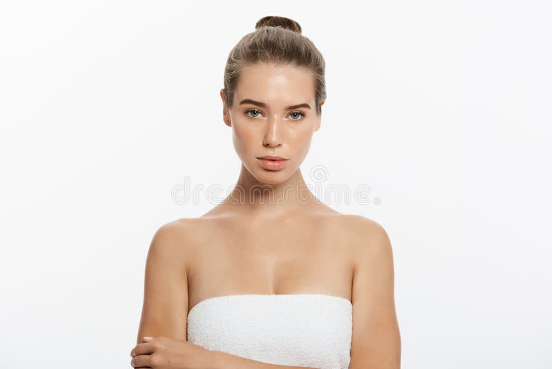 Beautiful girl with dark brown hair fixed behind, big eyes, dark eyebrows and naked shoulders looking at camera, a model