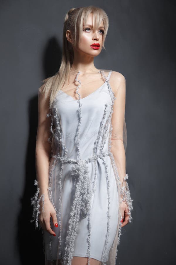 Beautiful girl in designer fashionable transparent clothes posing in studio.