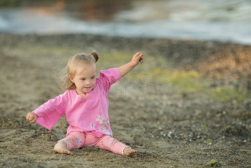 Beautiful girl with Down syndrome shows how a bird flies on the beach