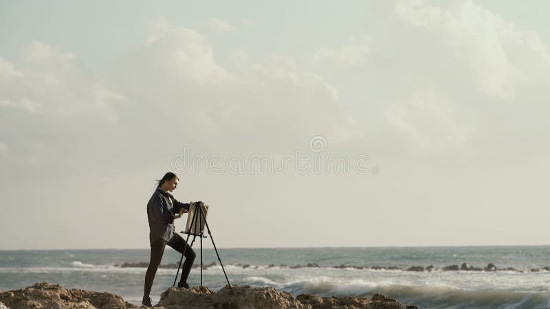 Beautiful girl drawing on easel on the background of the ocean