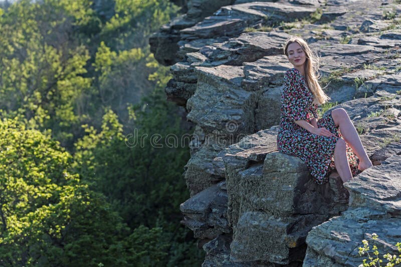 Beautiful girl in dress sits on rock in nature stock photography Beautiful girl in dress sits on rock in nature stock photography