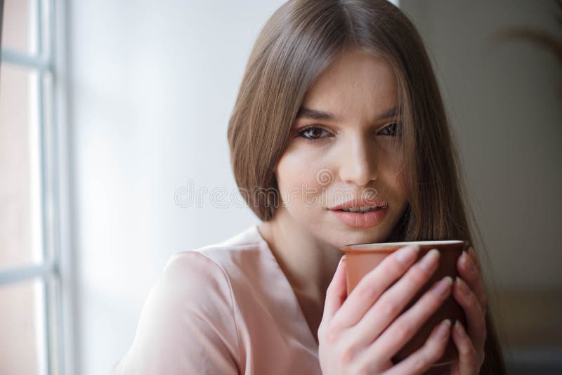 Beautiful Girl is Drinking Coffee and Smiling while Sitting at the Cafe ...