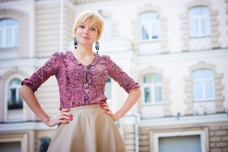 Beautiful girl with arms akimbo looks into camera. European street. Beautiful girl with arms akimbo looks into camera. European street