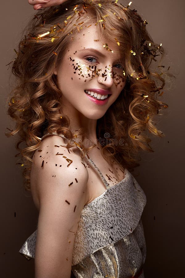 Beautiful girl in an evening dress and gold curls. Model in New Year`s image with glitter and tinsel. royalty free stock images Beautiful girl in an evening dress and gold curls. Model in New Year`s image with glitter and tinsel. royalty free stock images
