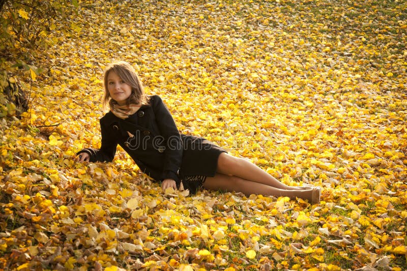 Beautiful girl on fallen yellow leaves