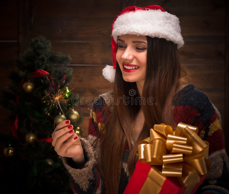 Beautiful girl holding a present near New Year tree