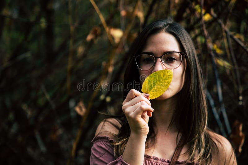 Beautiful girl holding a yellow leaf covering her mouth stock photography Beautiful girl holding a yellow leaf covering her mouth stock photography