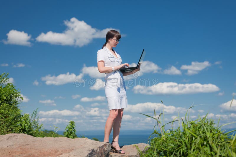 Beautiful girl with a laptop is on the stone