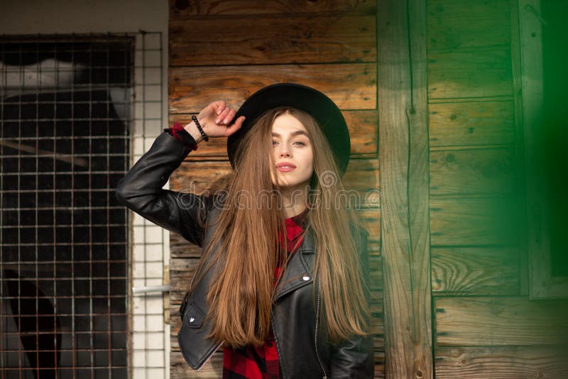 Beautiful girl with long hair and black hat, stands on the background of vintage old wooden house stock images Beautiful girl with long hair and black hat, stands on the background of vintage old wooden house stock images