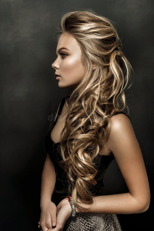 Beautiful girl with long wavy hair. fair-haired model with curly hairstyle and fashionable makeup.