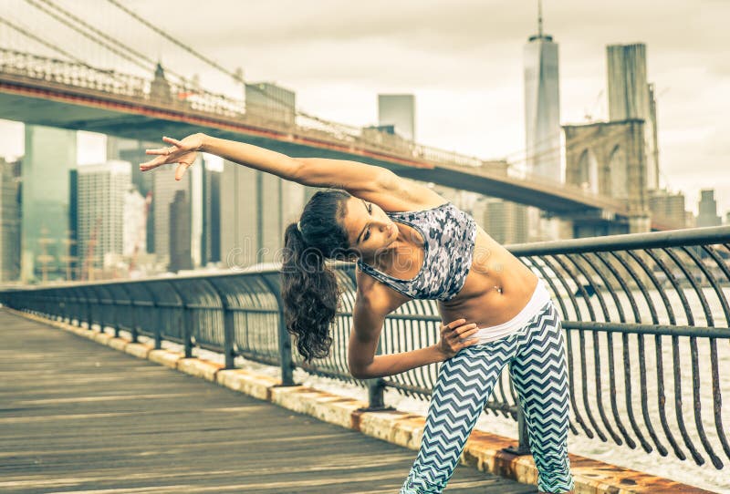 Beautiful girl making stretching before intense running in New york city
