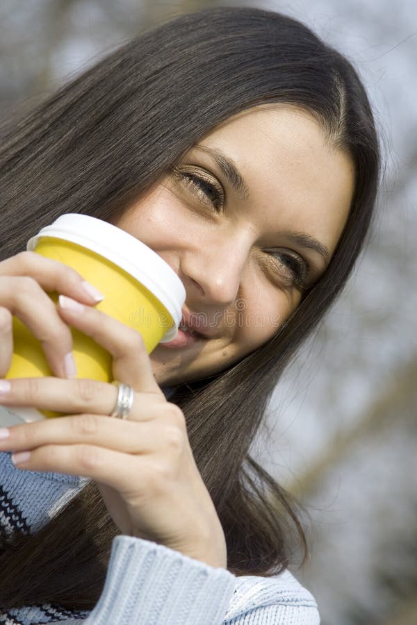 Beautiful girl in a park drinking coffee