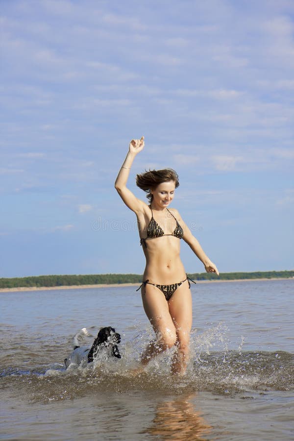 Beautiful girl playing on the beach with a dog stock photo