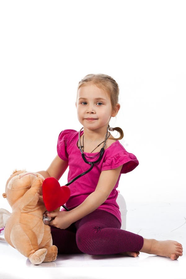 Beautiful girl playing doctor with a doll