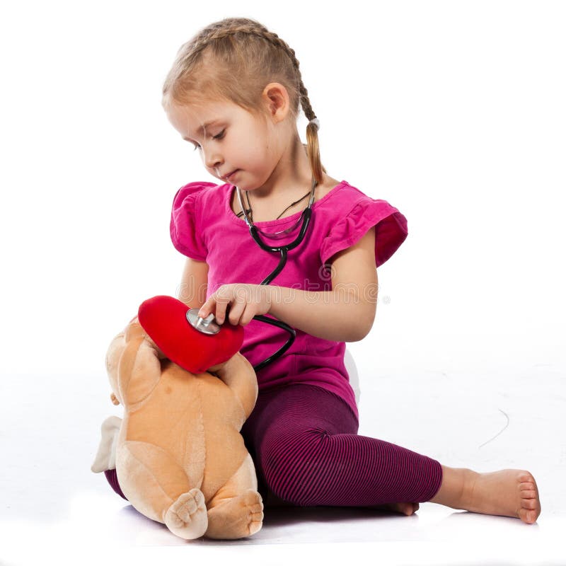 Beautiful girl playing doctor with a doll