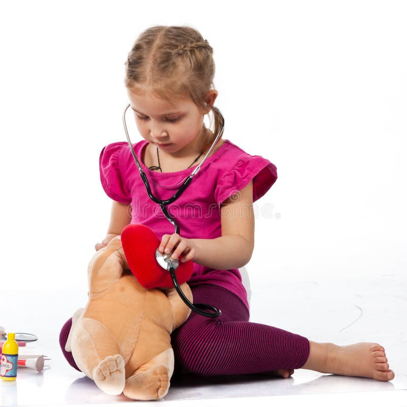 Beautiful girl playing doctor with a doll