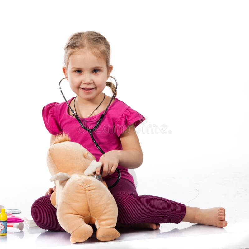 Beautiful girl playing doctor with a doll