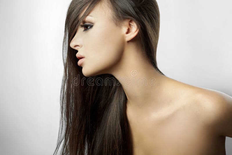 Krásná dívka v profilu, s dlouhými vlasy na bílém pozadí.