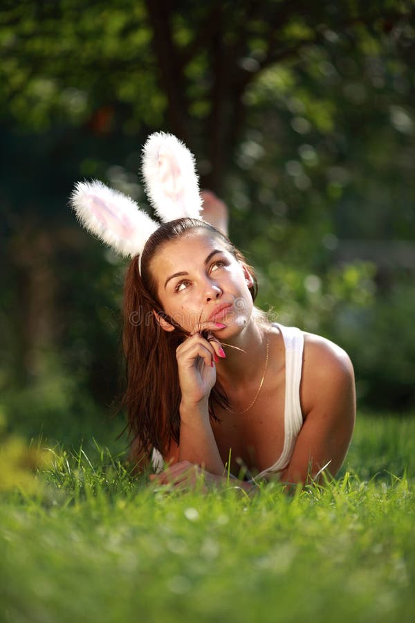 Beautiful girl with rabbit ears lies on a grass