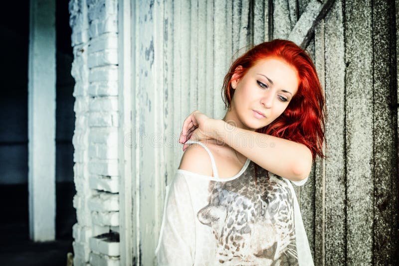 Beautiful girl with red hair outdoor against wooden doors