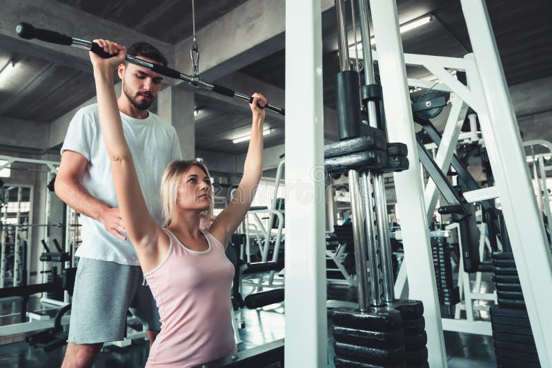 Beautiful Girl is Rowing Exercise With Bodybuilder Equipment in Fitness Club.,Portrait of Strong Woman doing Working Out Calories. Burning in Gym With Trainer stock image Beautiful Girl is Rowing Exercise With Bodybuilder Equipment in Fitness Club.,Portrait of Strong Woman doing Working Out Calories. Burning in Gym With Trainer stock image