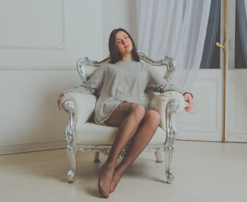 Beautiful girl in shirt sitting in a vintage chair.