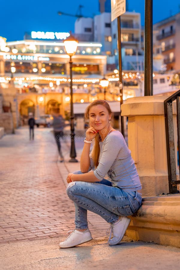 Beautiful girl sitting by the docs in the evening time