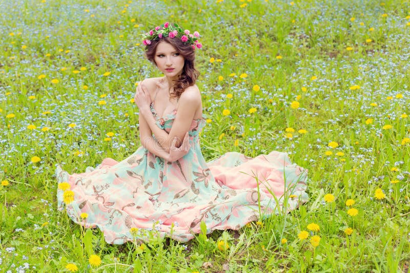 Beautiful girl sitting on the ground near the wall in jeans and a white blouse , her hair develops wind