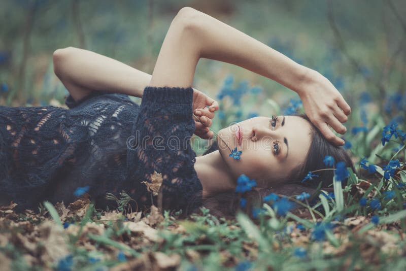 Beautiful girl among the snowdrops in the forest