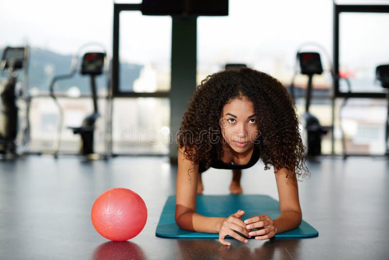 Beautiful girl in sportswea leaning on her elbows doing exercise for abdominals at gym