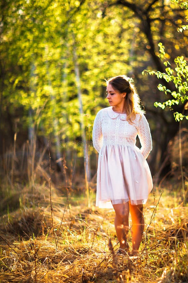 Beautiful Girl Standing In A Field On A Sunset Background Stock Image