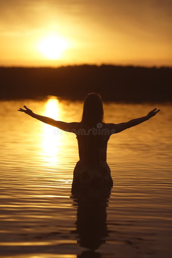 Beautiful girl in water on sunset