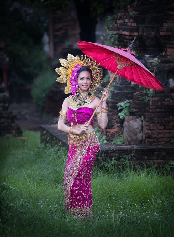 Beautiful girl wearing Thai dress and umbrella flower flow background old temple local country thailand