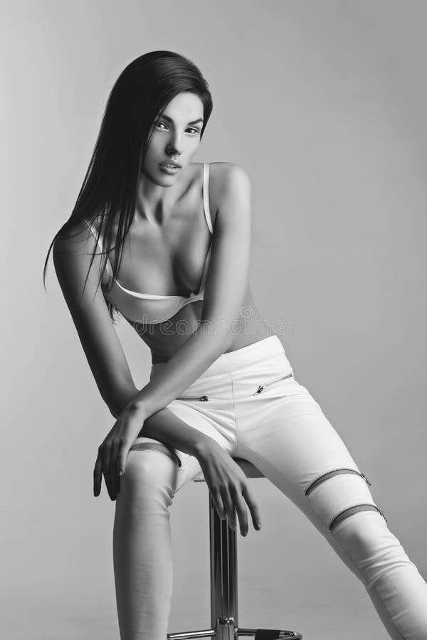 Beautiful girl in white bra and leather pants. Beautiful young slim woman in white bra and leather pants with zippers. Fashion shot. Over white background. Copy stock image Beautiful girl in white bra and leather pants. Beautiful young slim woman in white bra and leather pants with zippers. Fashion shot. Over white background. Copy stock image