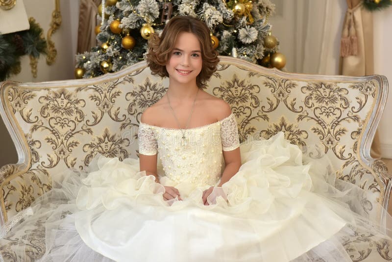 Beautiful girl in white Victorian dress at the Christmas tree is