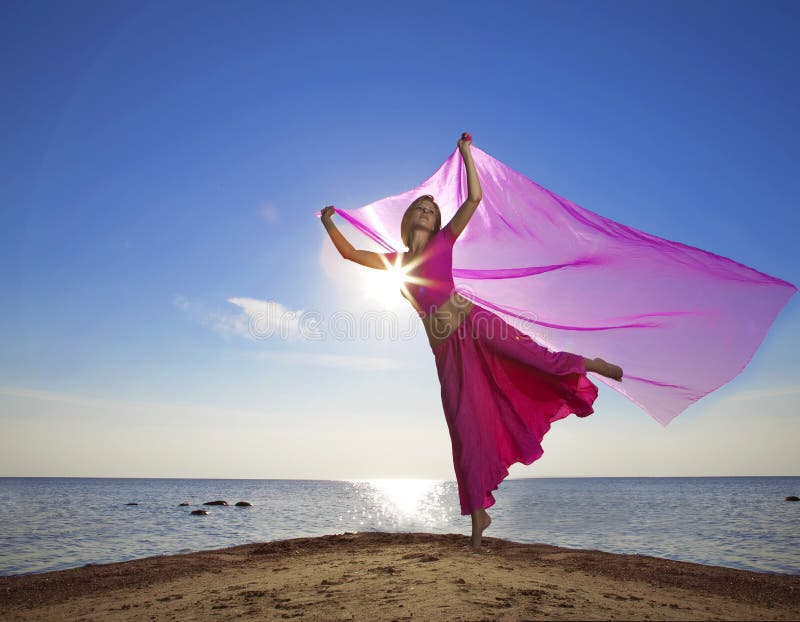 Beautiful girl who jump on the beach at sunset