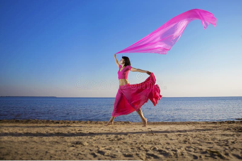 Beautiful girl who jump on the beach at sunset