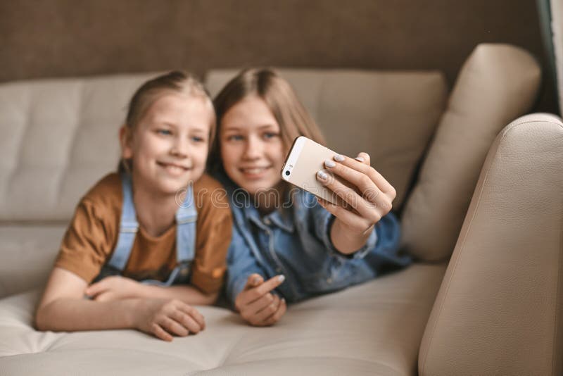 Beautiful Girls Take Selfies On Their Phone While Lying On The Sofa 