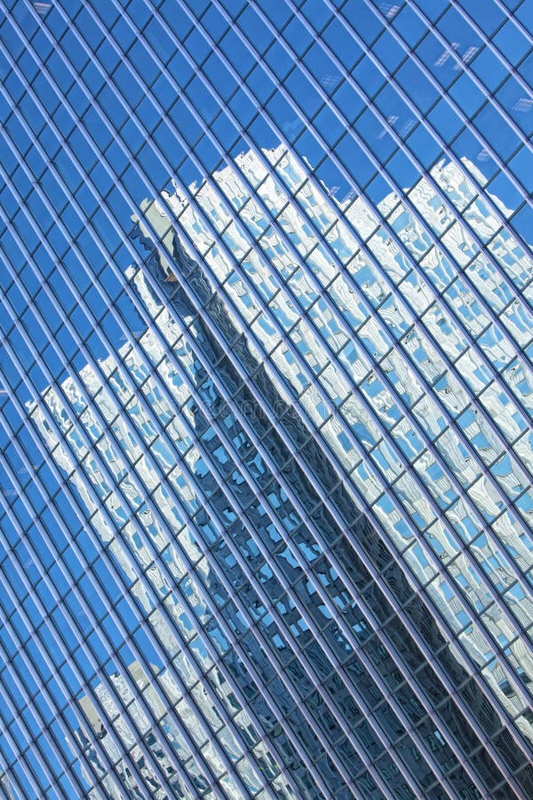 Beautiful glass office building with blue reflections of surrounding buildings