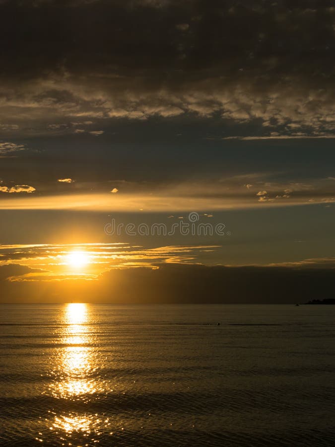 Beautiful golden sunset at calm adriatic sea, last beam of the sun makes a golden path on waveless water surface. Enlighted with o