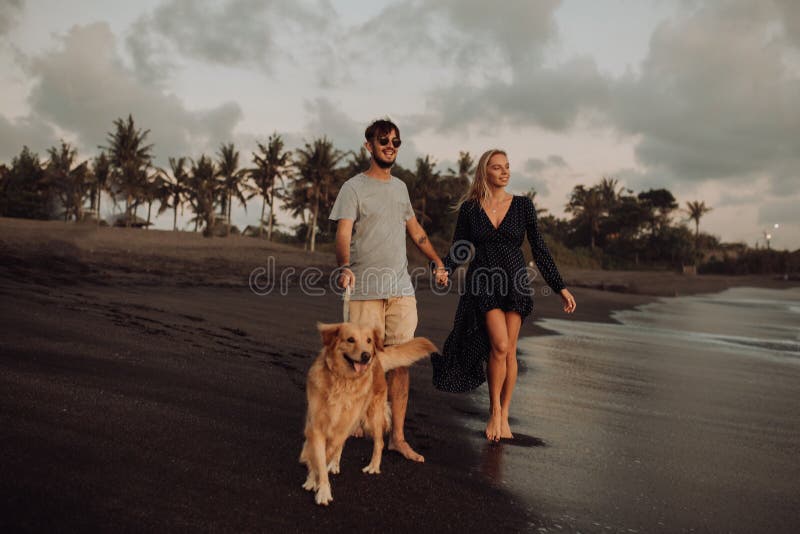 Beautiful happy laugh young hipster couple with golden retriever on beach. ocean an sand. waves. concepte of freedom and stock photos Beautiful happy laugh young hipster couple with golden retriever on beach. ocean an sand. waves. concepte of freedom and stock photos